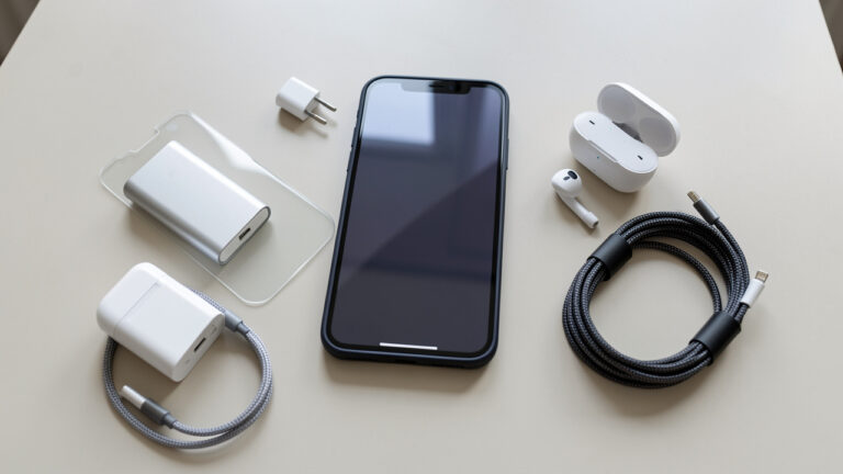 Smartphone entouré d’une coque de protection, d’un verre trempé, d’un chargeur, d’un câble, d’écouteurs sans fil et d’une batterie externe.