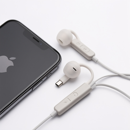 Écouteurs filaires USB-C avec module de commande, disposés à côté d’un smartphone compatible dans un environnement lumineux et épuré.
